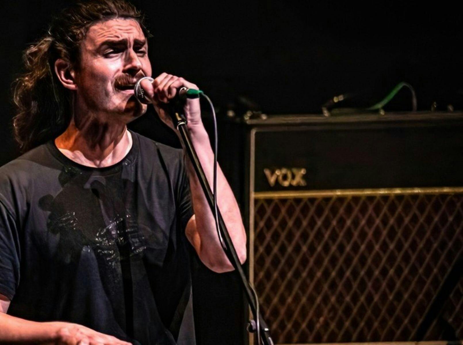 Man singing into microphone next to an amplifier