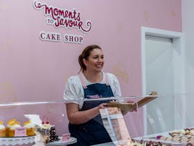 Sally holding cake box behind serving bench
