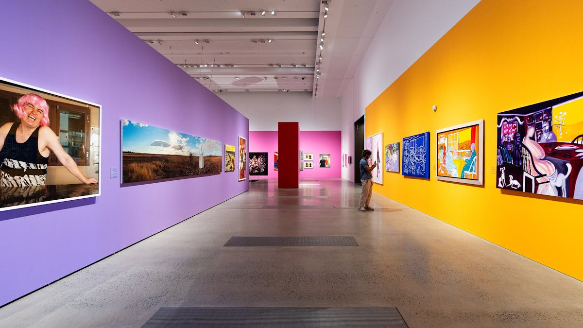 An internal photo of a wide hallway with colourful walls and art pieces hung