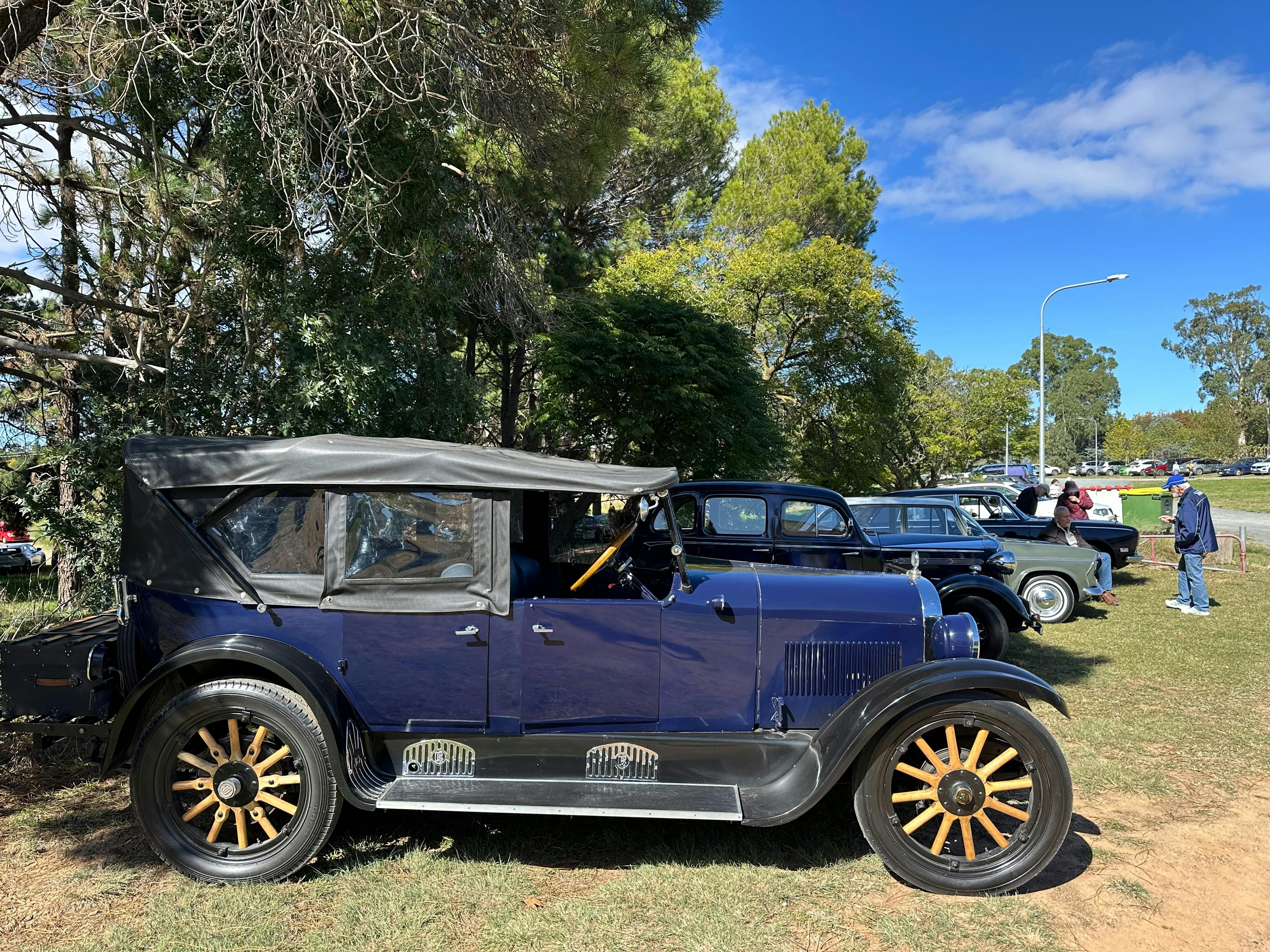 Vintage dark blue car from the side with yellow spokes and soft top