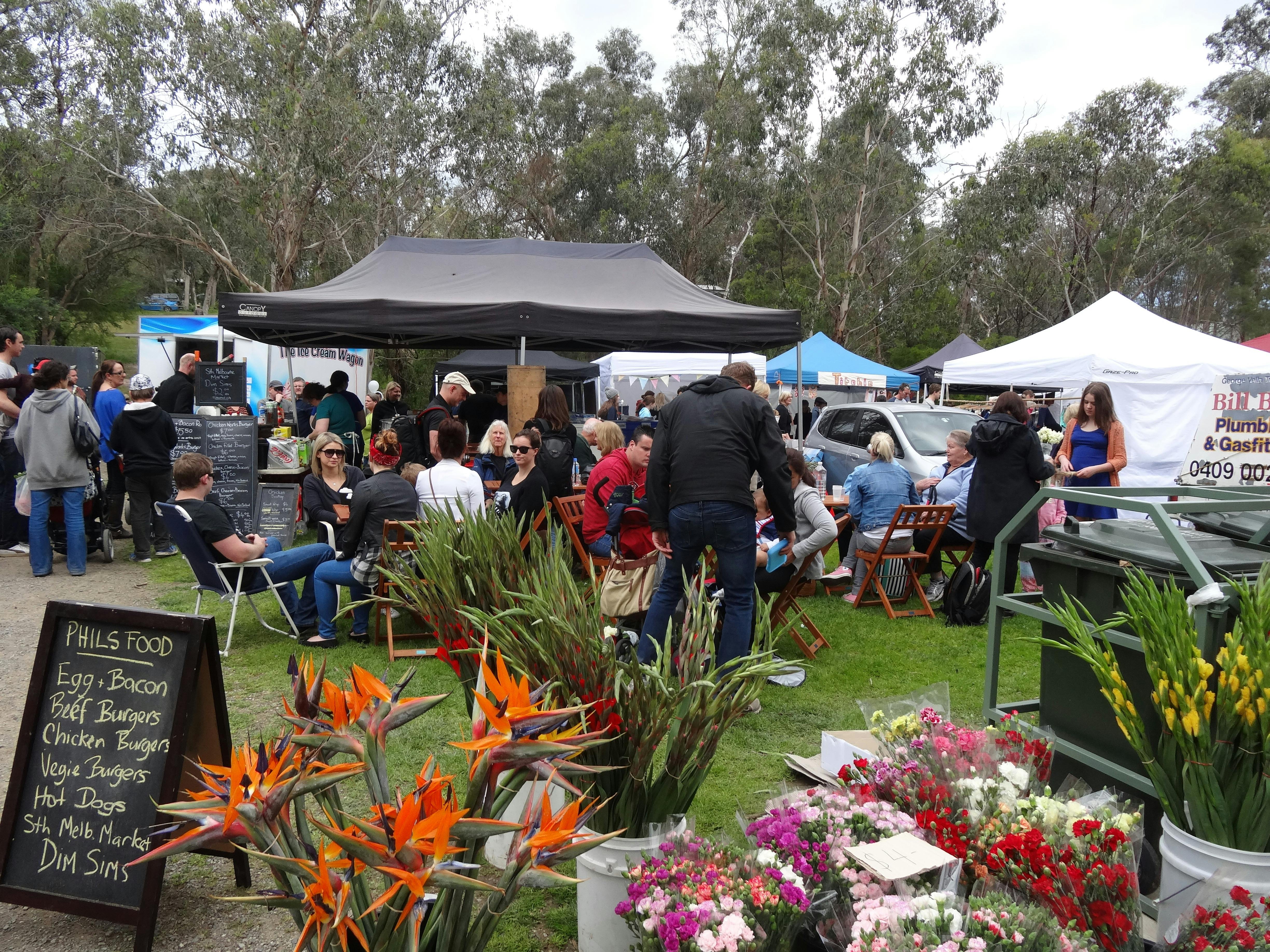 Flowers and people gathered at market in bushland setting