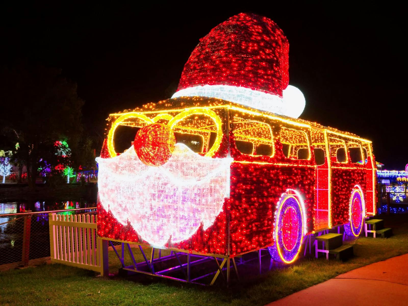 A santa themed bus, lit up with red and yellow lights