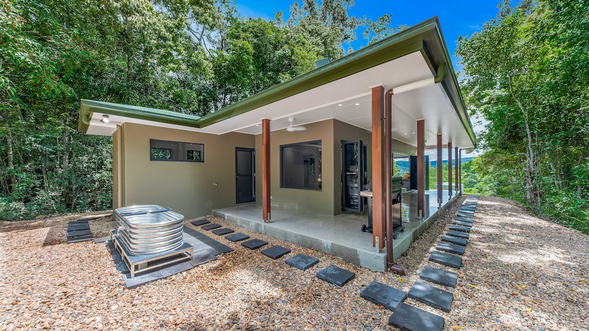 Back of accommodation, showing the outdoor bath and pavers surrounding the house.