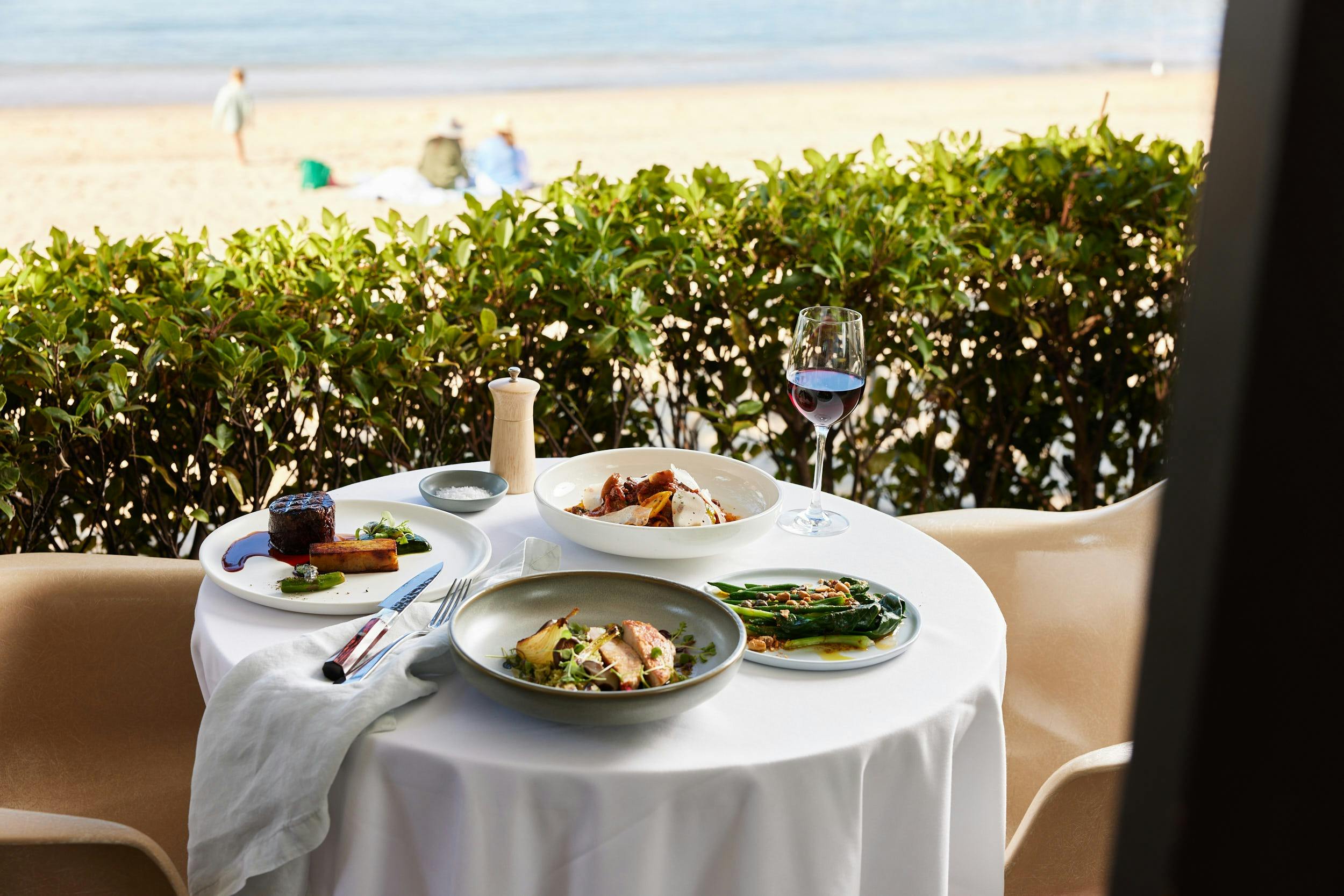 Eye fillet, tagliatelle, chicken dish and brocollini side on table with water views