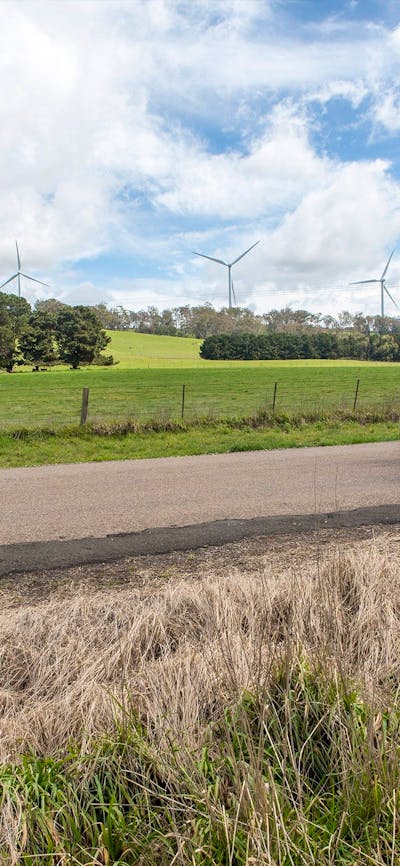 Two cyclists passing 5 wind turbines.