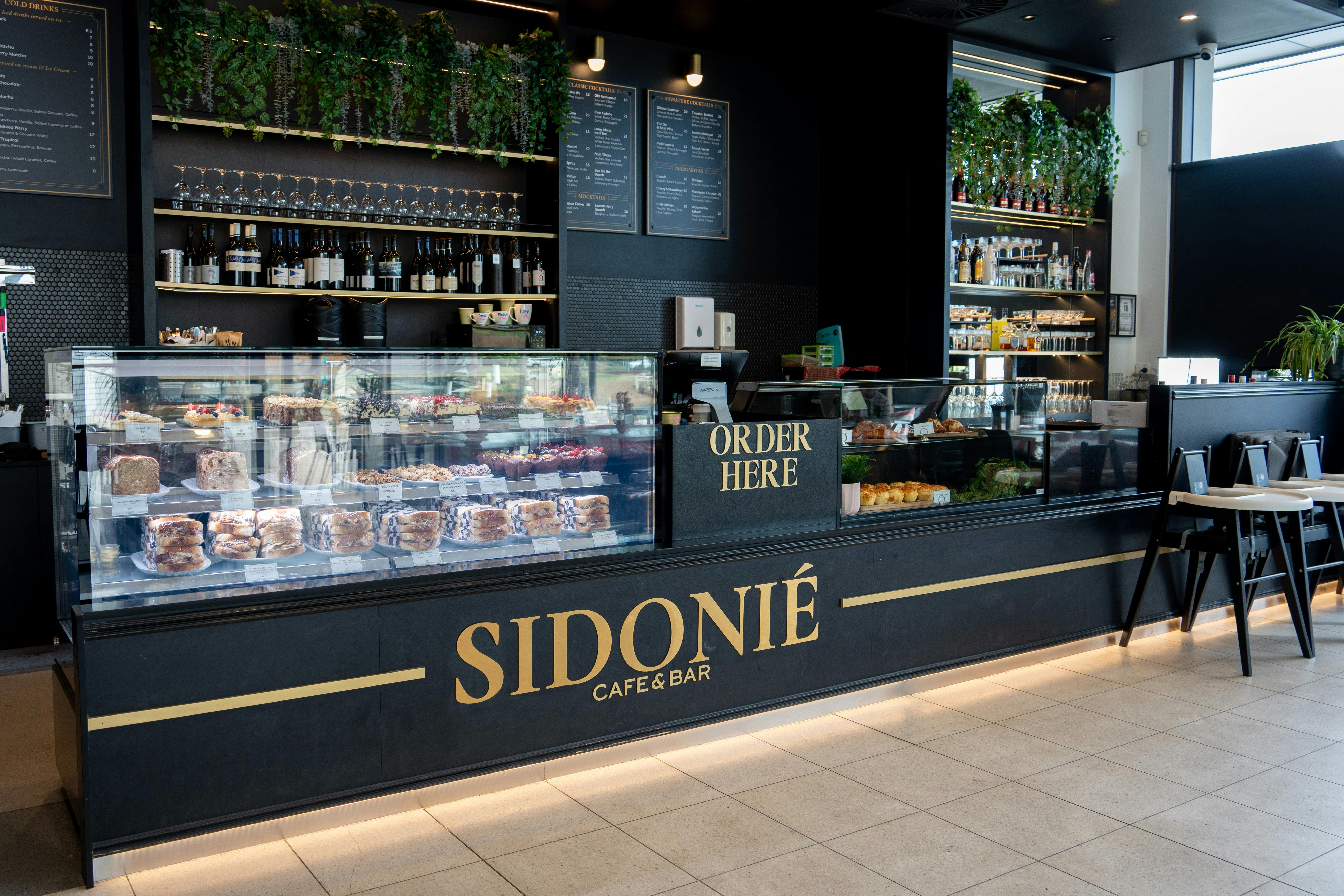 Sidonié Newport counter with cabinet treats, drinks menus and gold signage.