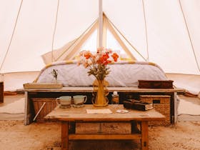 nterior of a luxury bell tent with a queen bed and seating area at Salty Sands Retreats.