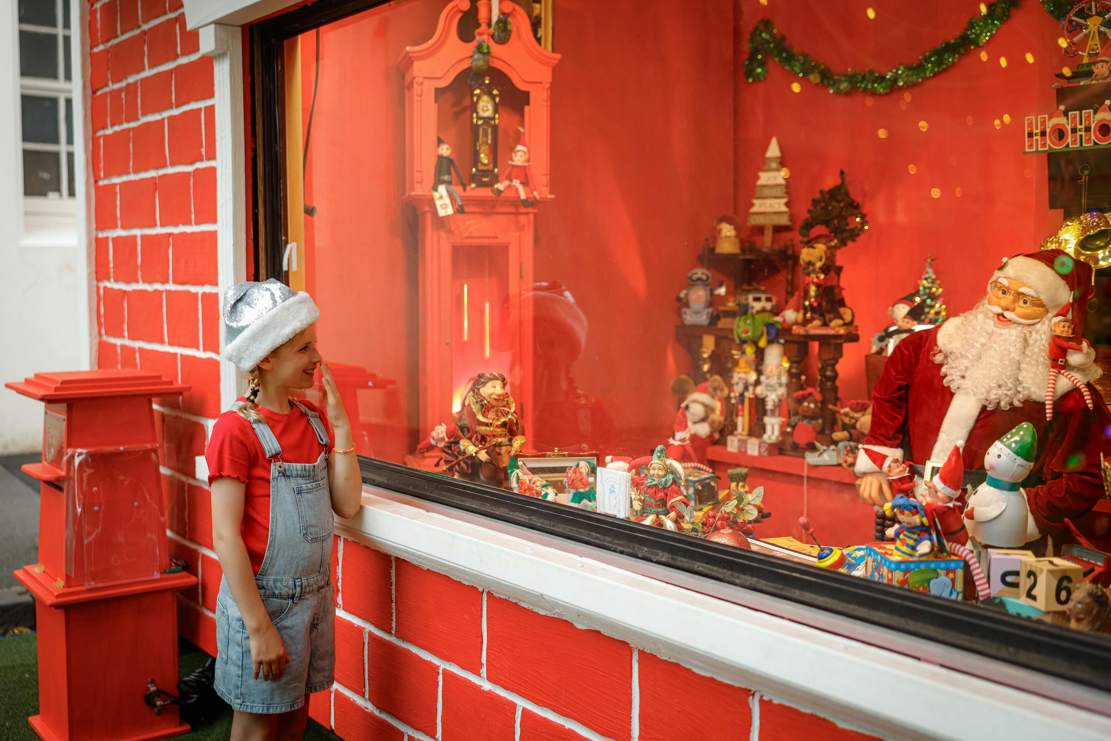 A girl in red stands and looks into the Magical Christmas Emporium