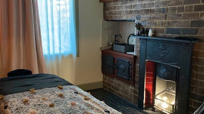 Massage room with subtle light and historical features including fireplace .