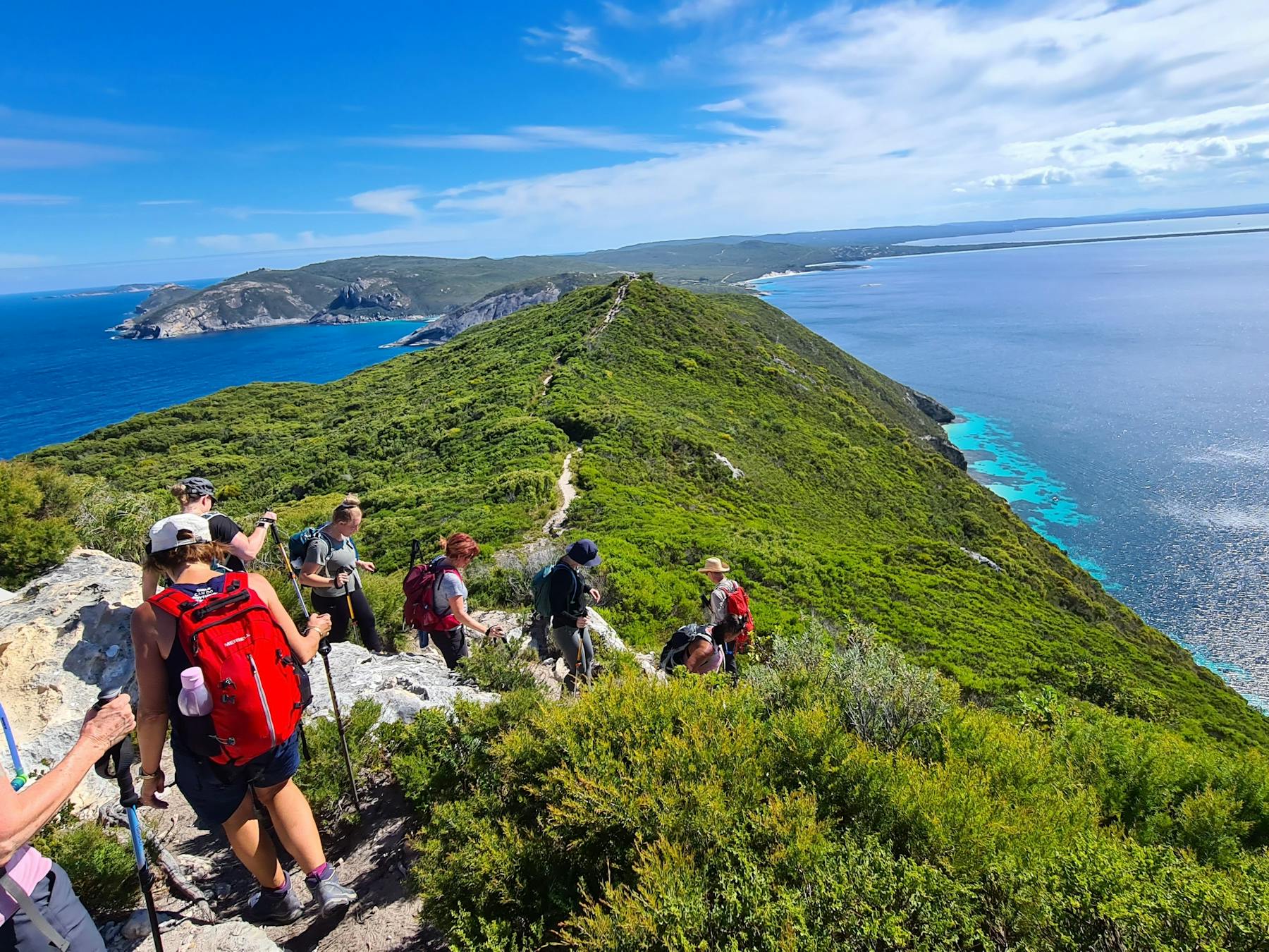 Happy hikers walking up coastal headland in Albany