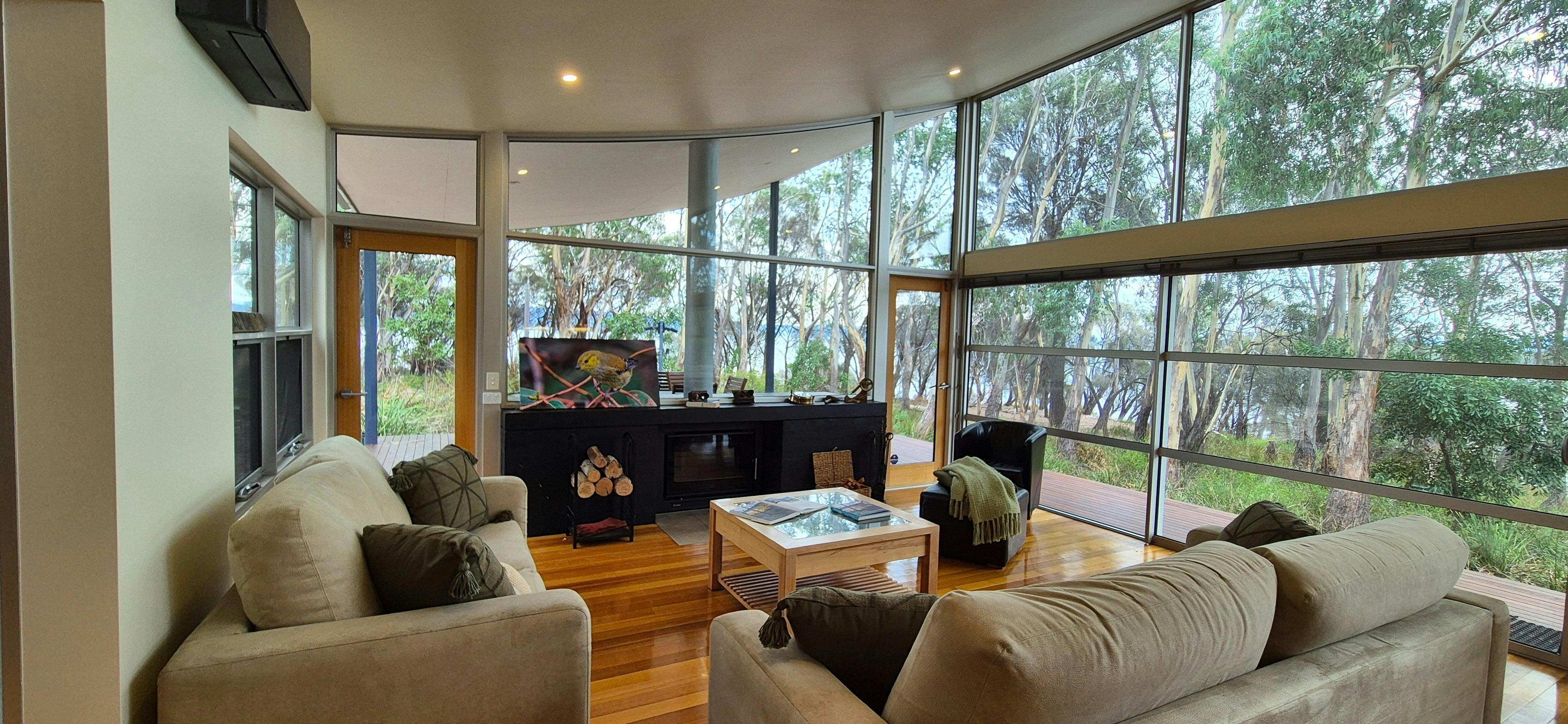 Living room with fireplace, view to the BBQ area and alfresco and ocean views