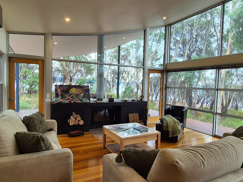 Living room with fireplace, view to the BBQ area and alfresco and ocean views