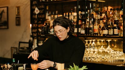 Person making a cocktail at a bar