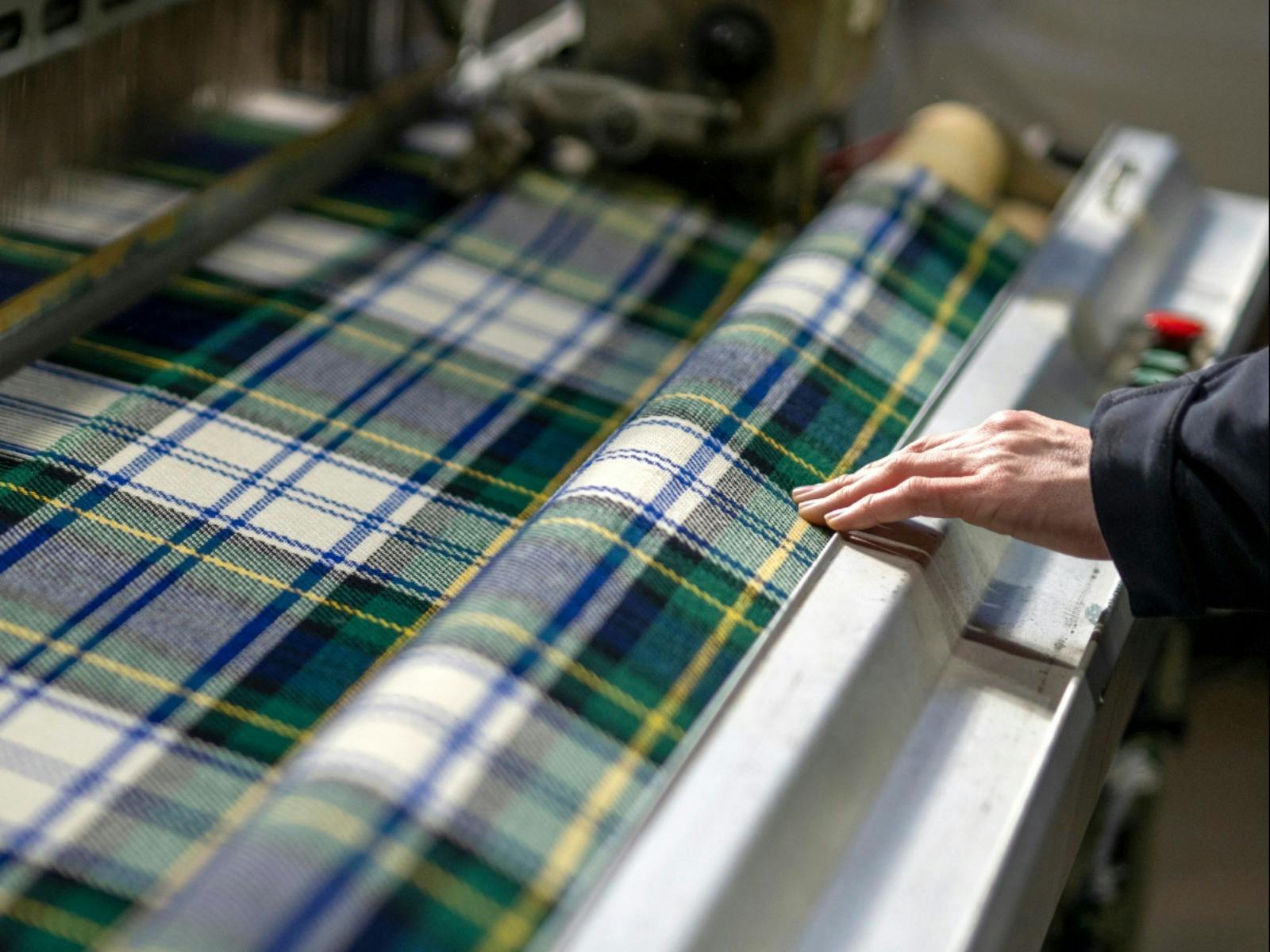 Blue, white and green tartan blanket during production with hand checking wool fibres.