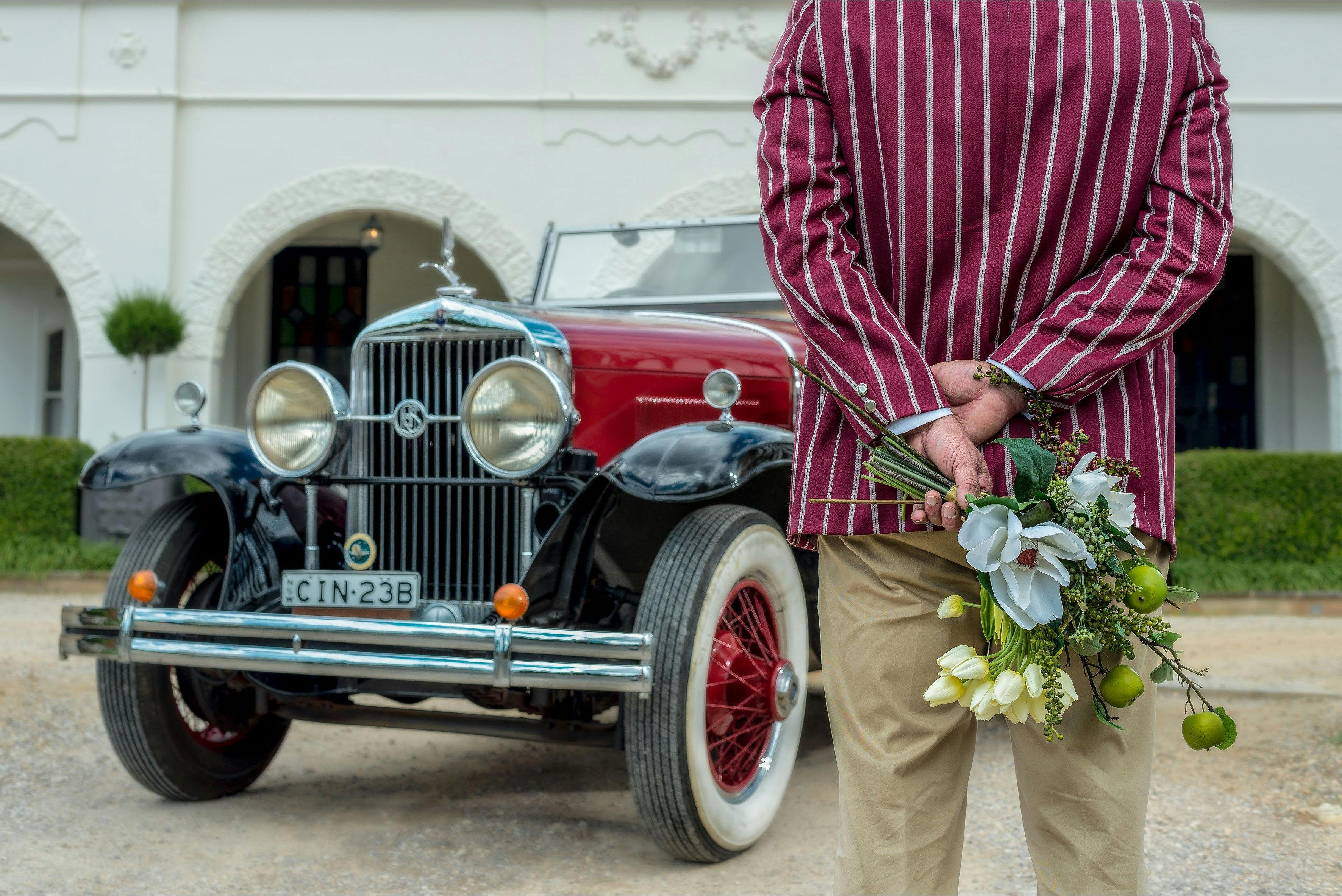 Vintage car and driver in front of historic hotel
