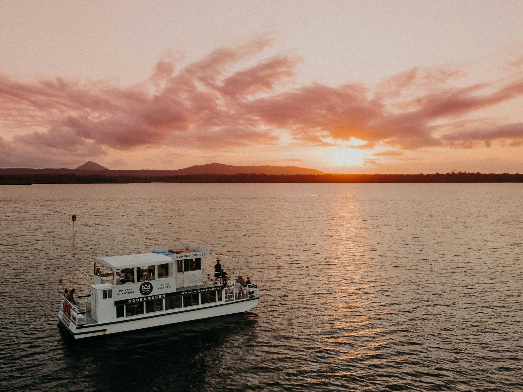 The Noosa Queen on Lake Cooroibah with the sun setting in the background