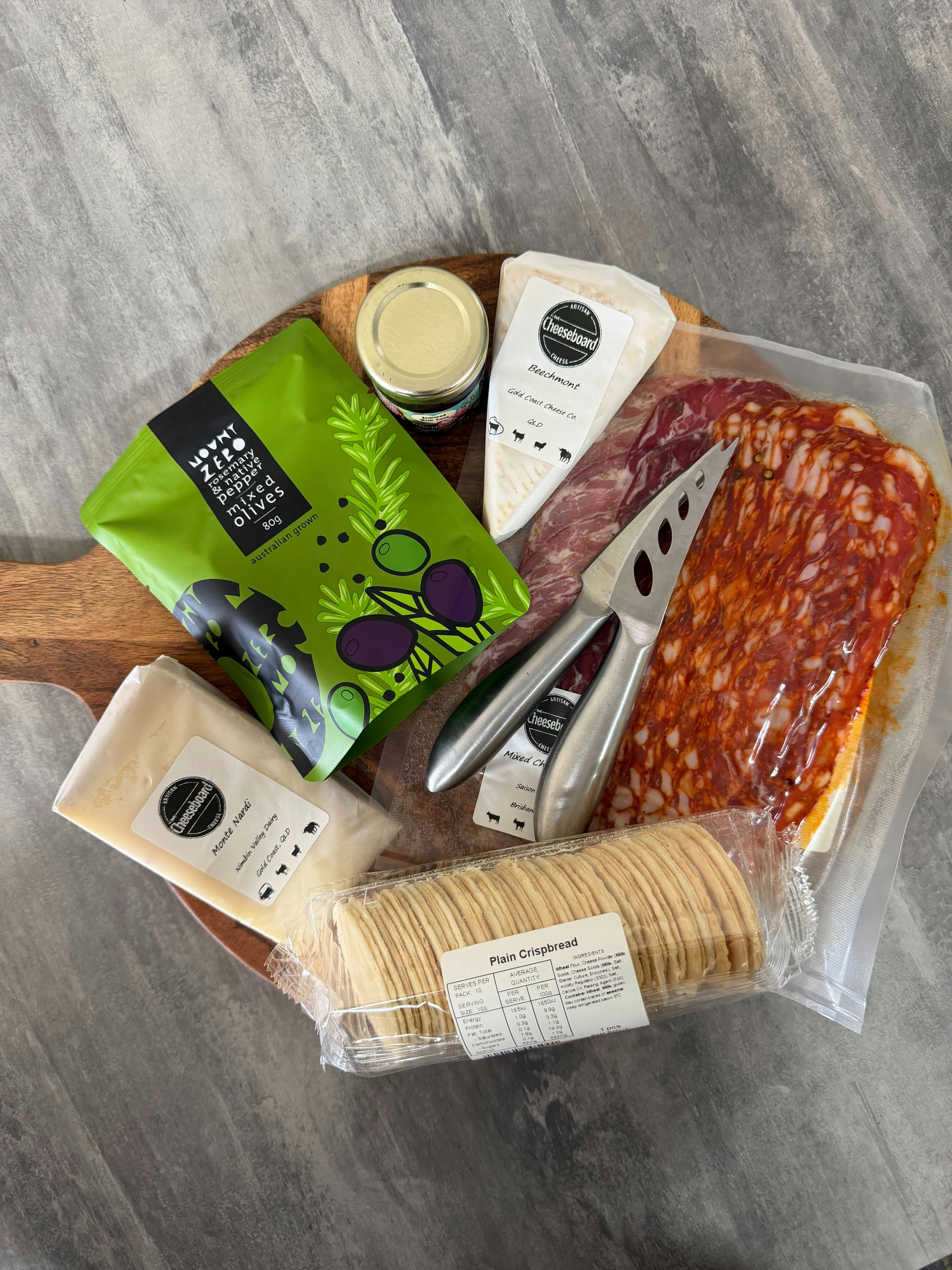 Build your own cheese board options on board, birds eye view. Cheese, meats, olives, jam and cracker