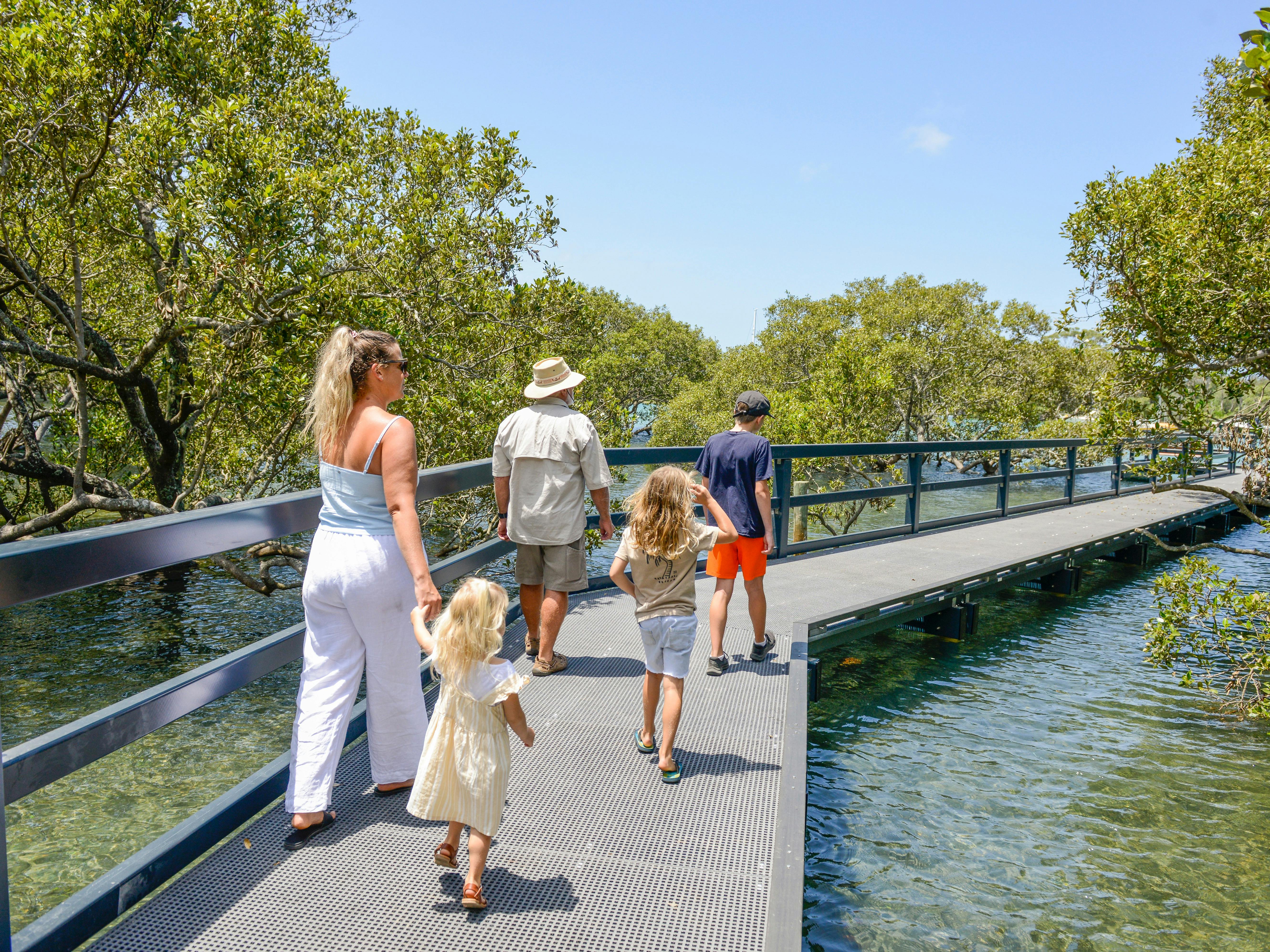 family walk on built path above shallow water