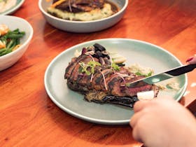 Close-up of a steak on a green plate with sides on a wooden table