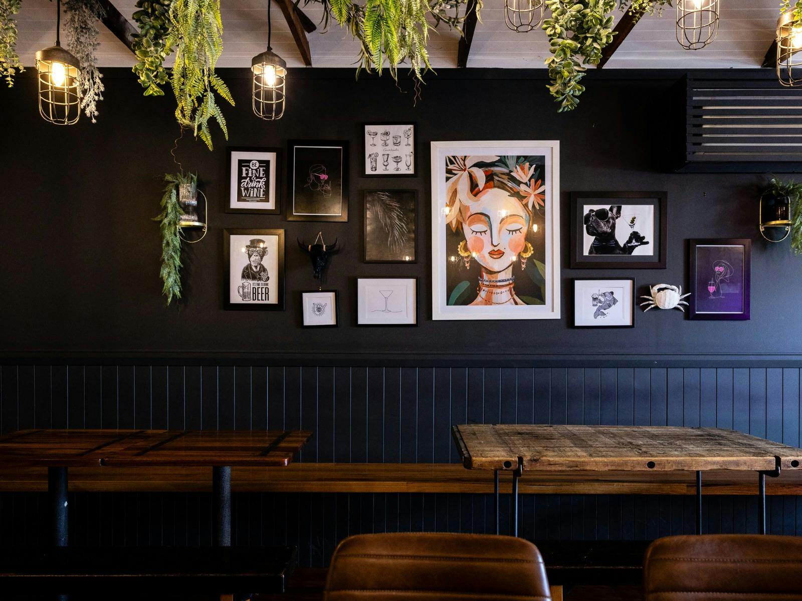 The Rutledge Bar & Eats interior seating area,  art frames on dark wall with plants