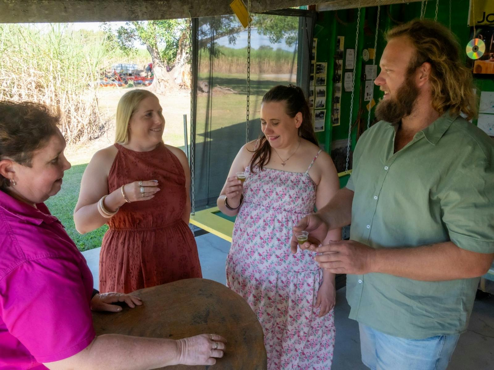 4 people holding sugar cane juice in small cups smiling at each other 4 people holding sugar cane juice in small cups smiling at each other