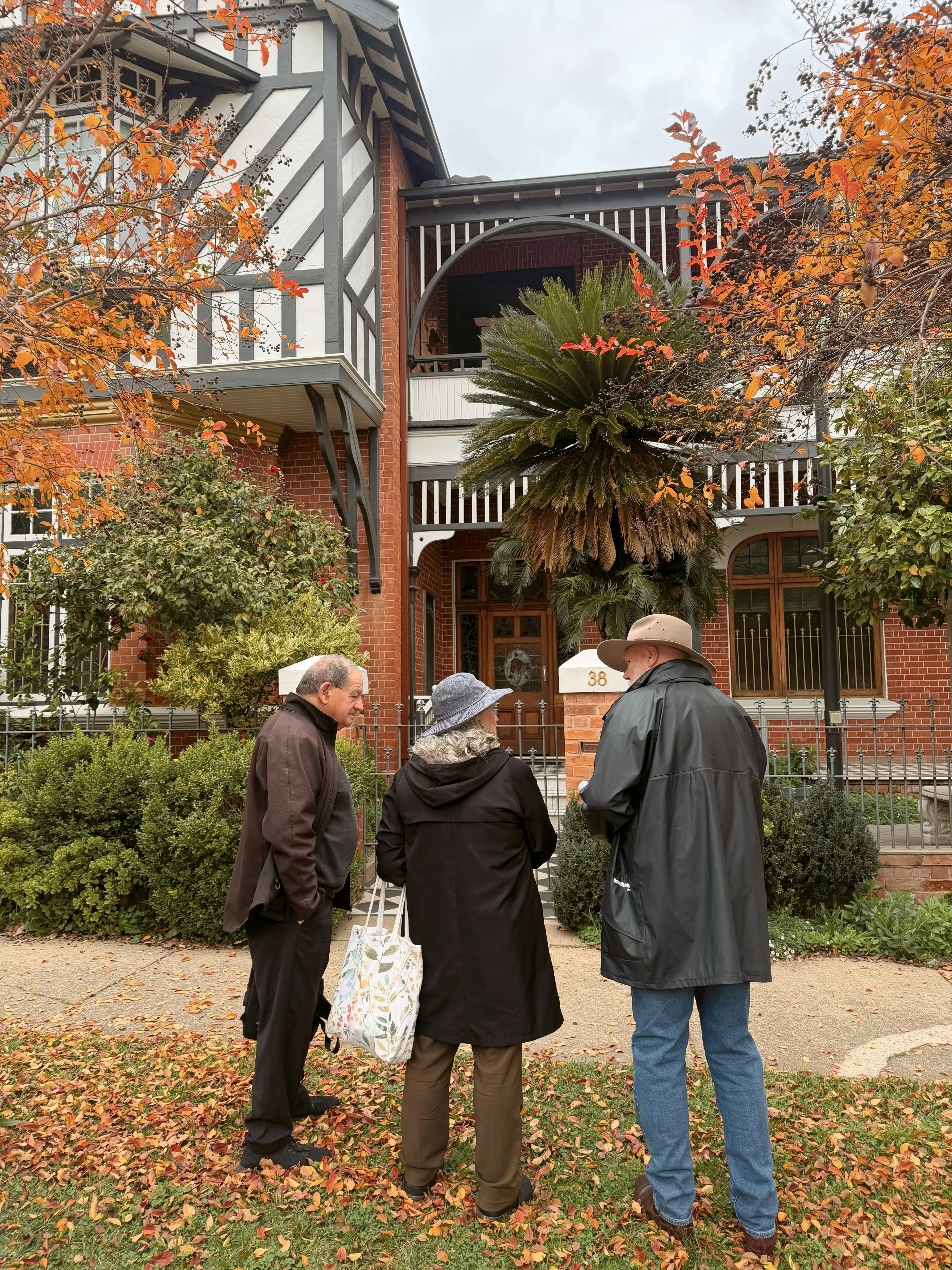 A couple and guide stand outside a historical building on a architectural tour of Wagga Wagga