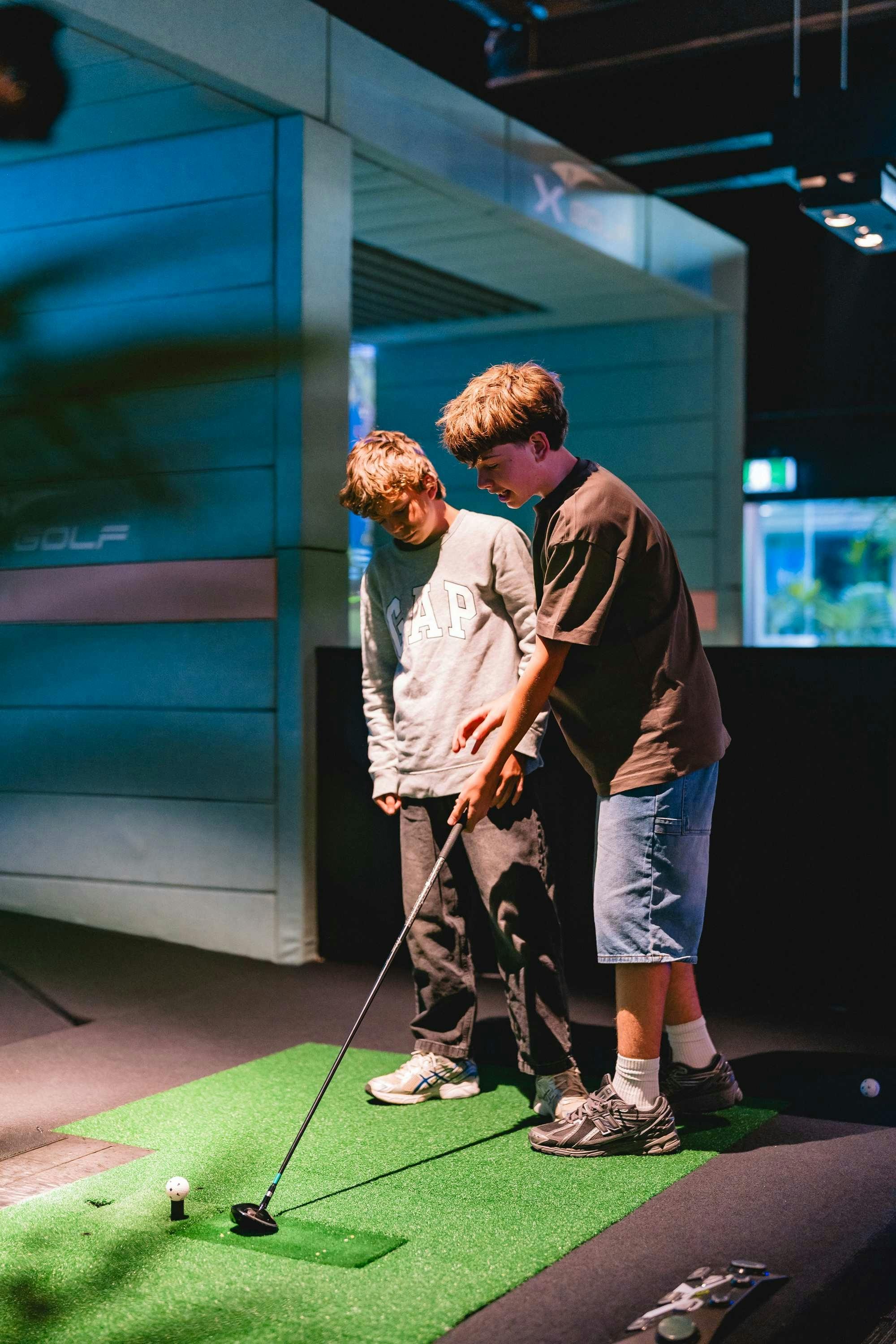 Kids Playing Golf Simulator at X-Golf Venue