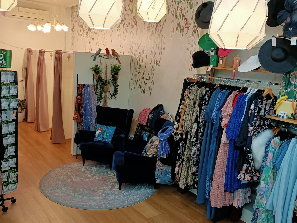 Three roomy change rooms with pink curtains and two blue velvet  wingback chairs to sit and relax.