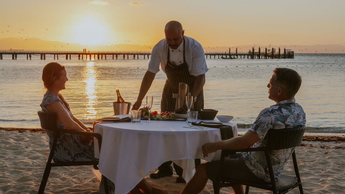 Couple being served dinner on the beach