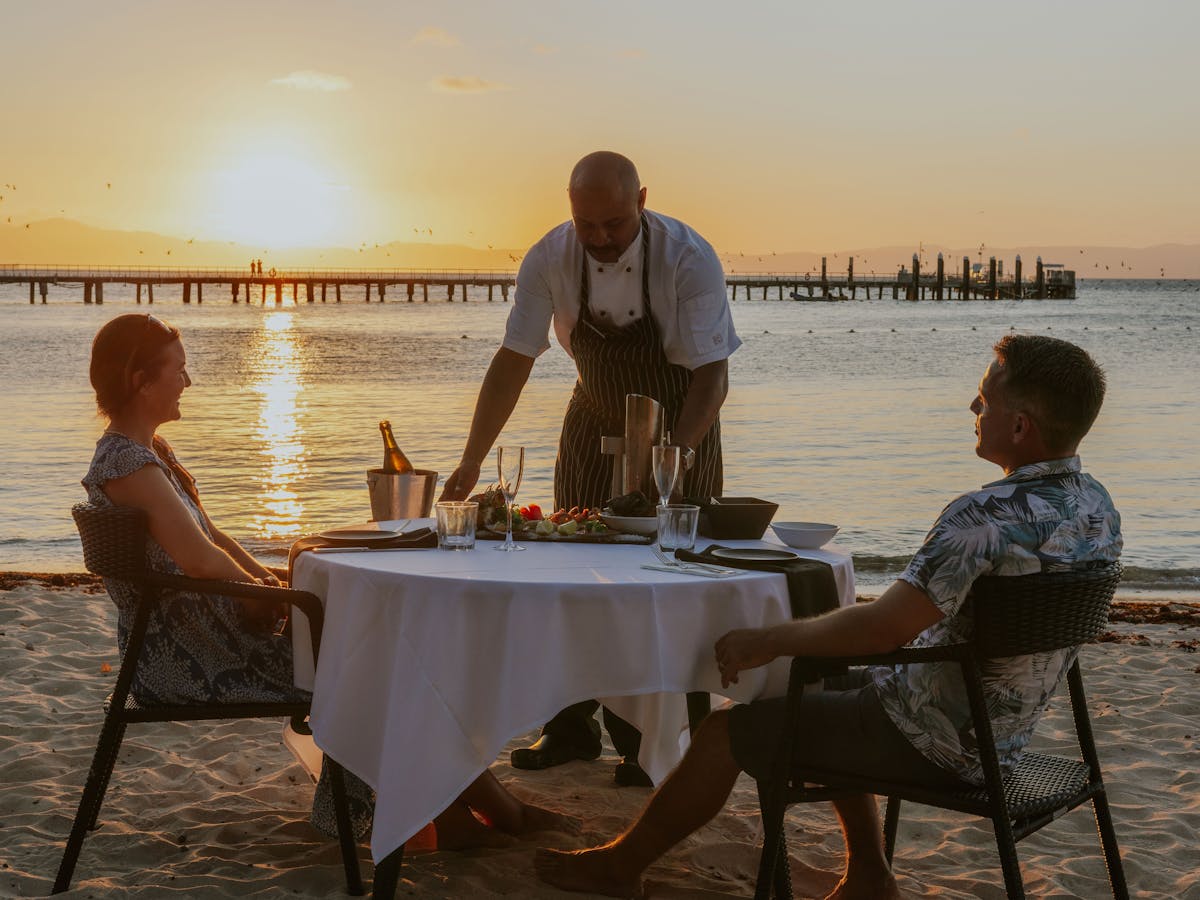 Couple being served dinner on the beach