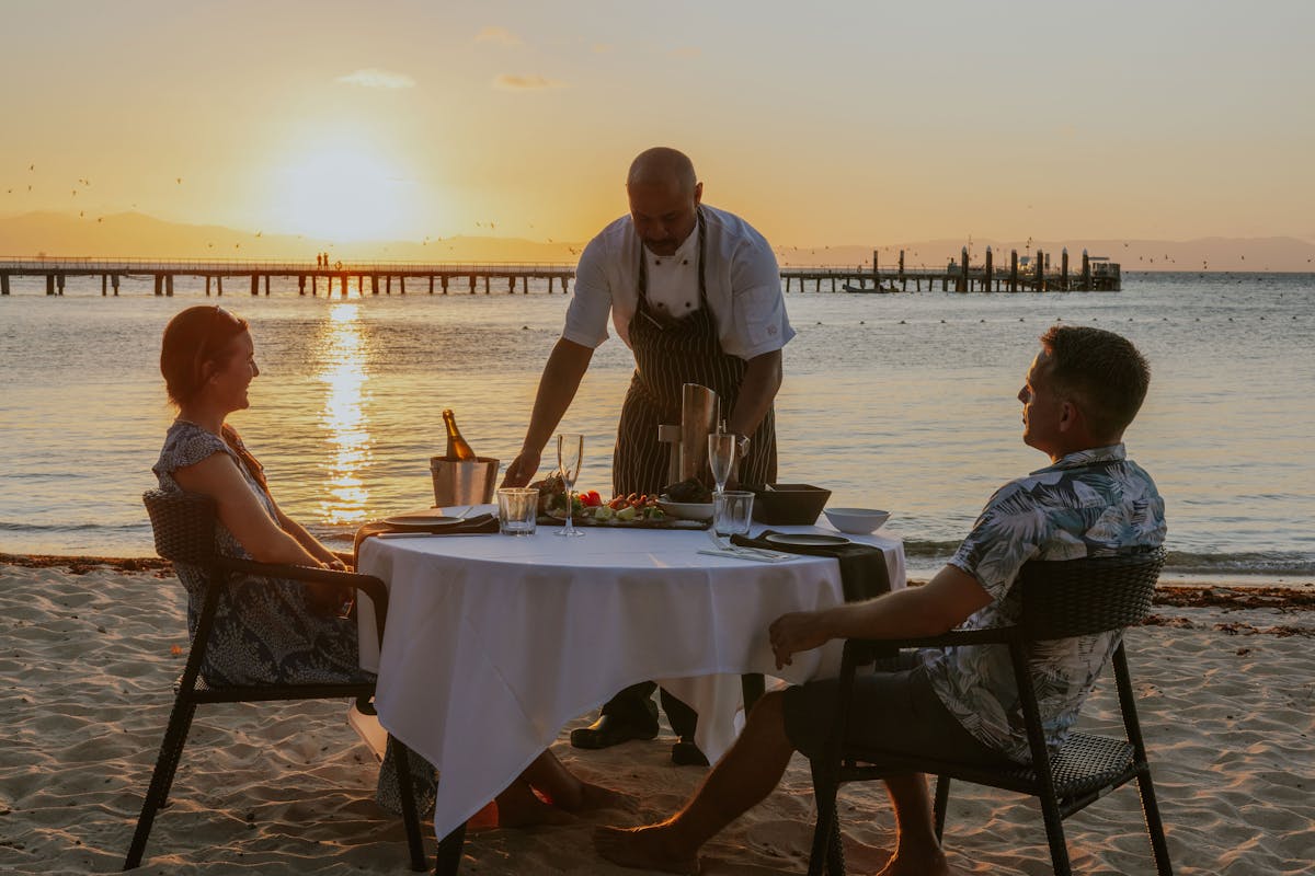 Couple being served dinner on the beach