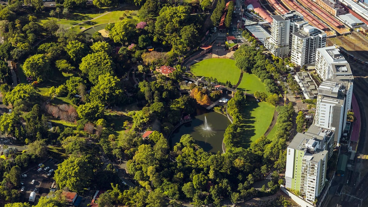 Aerial view of Roma Street Parkland showing dense green spaces of trees and lawn and a lake