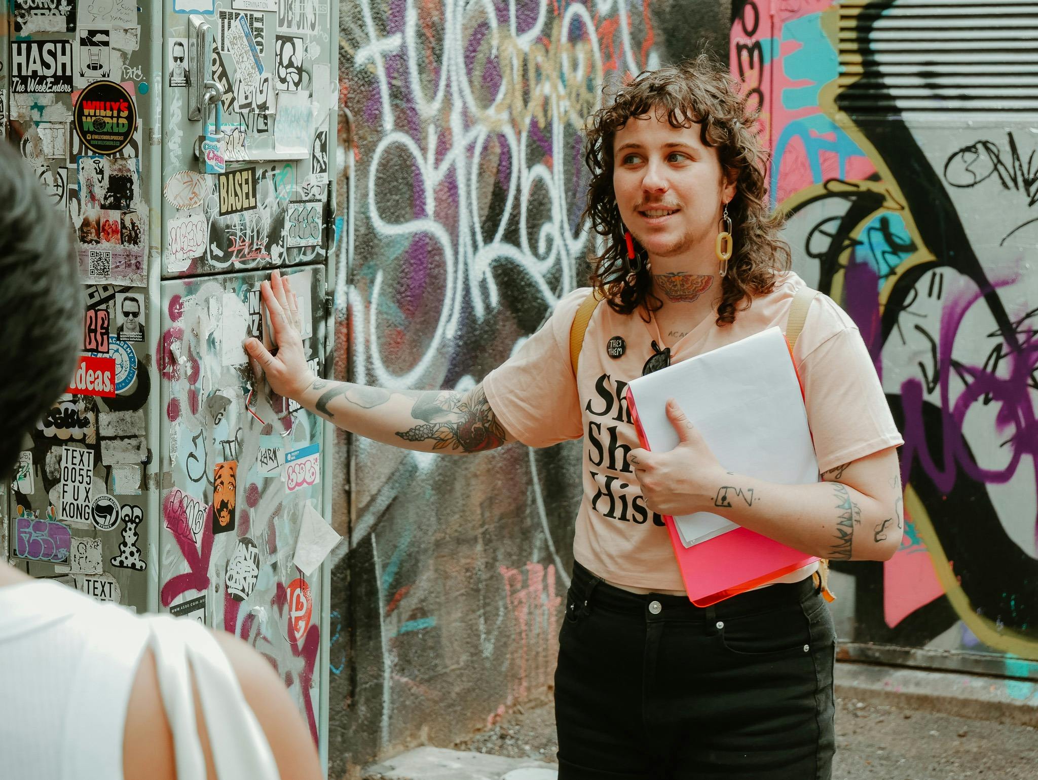 Tour guide Zev is touching wall covered in street art