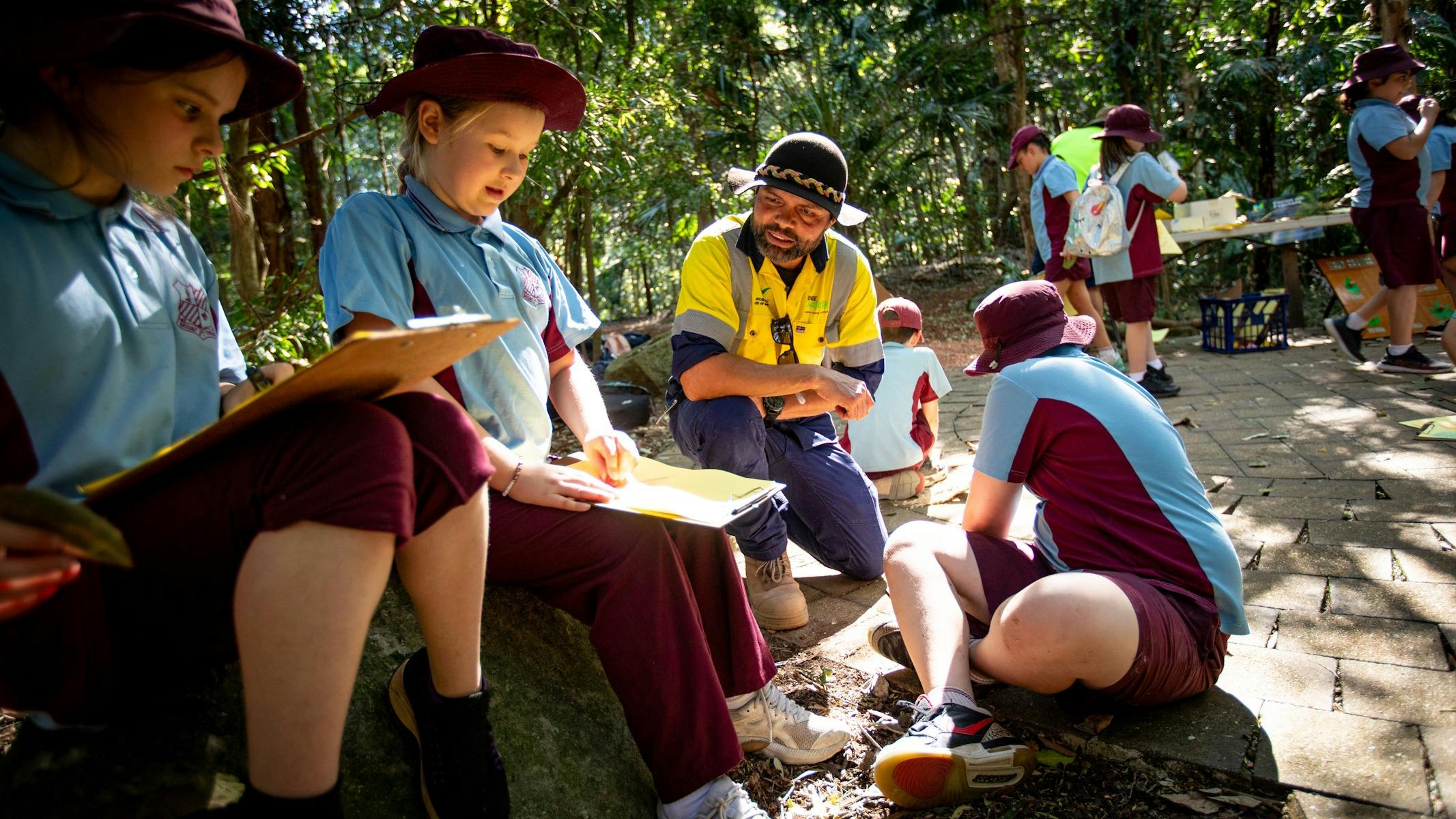 Local students in rainforest writing in notebooks