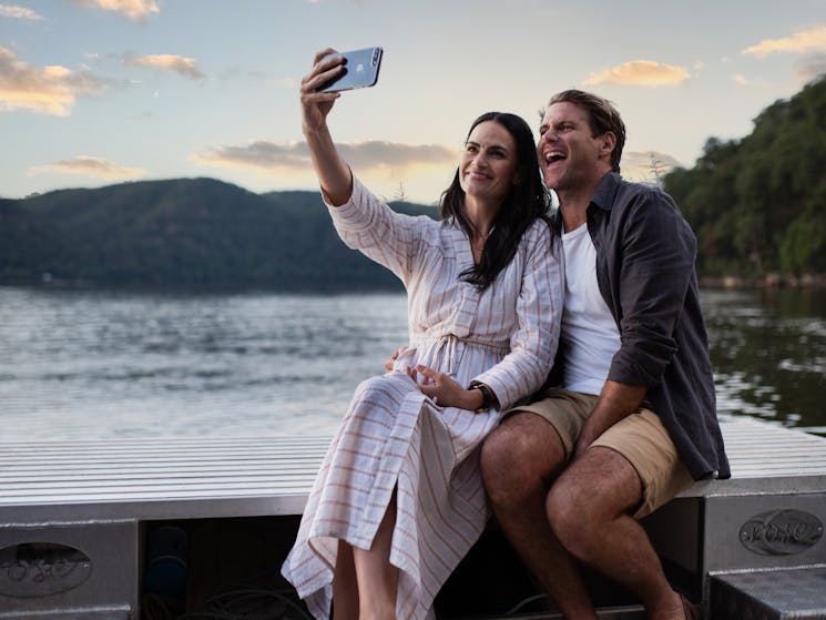 Couple taking selfie on ultimate pearl farm experience at sunset on the Lower Hawkesbury River