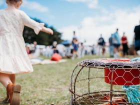 Little girl swaying next to a lobster pot - Beachport Crayfish Festival in background
