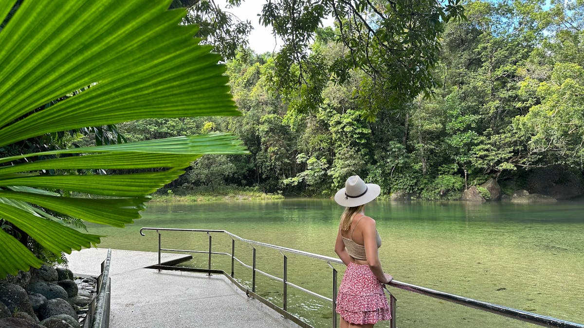 Woman standing at the edge of the Babinda Boulders swimming area with lush rainforest surrounding