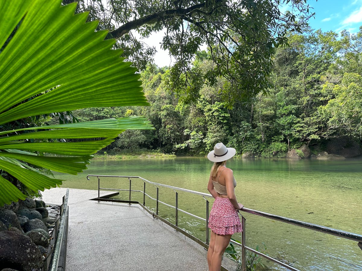 Woman standing at the edge of the Babinda Boulders swimming area with lush rainforest surrounding