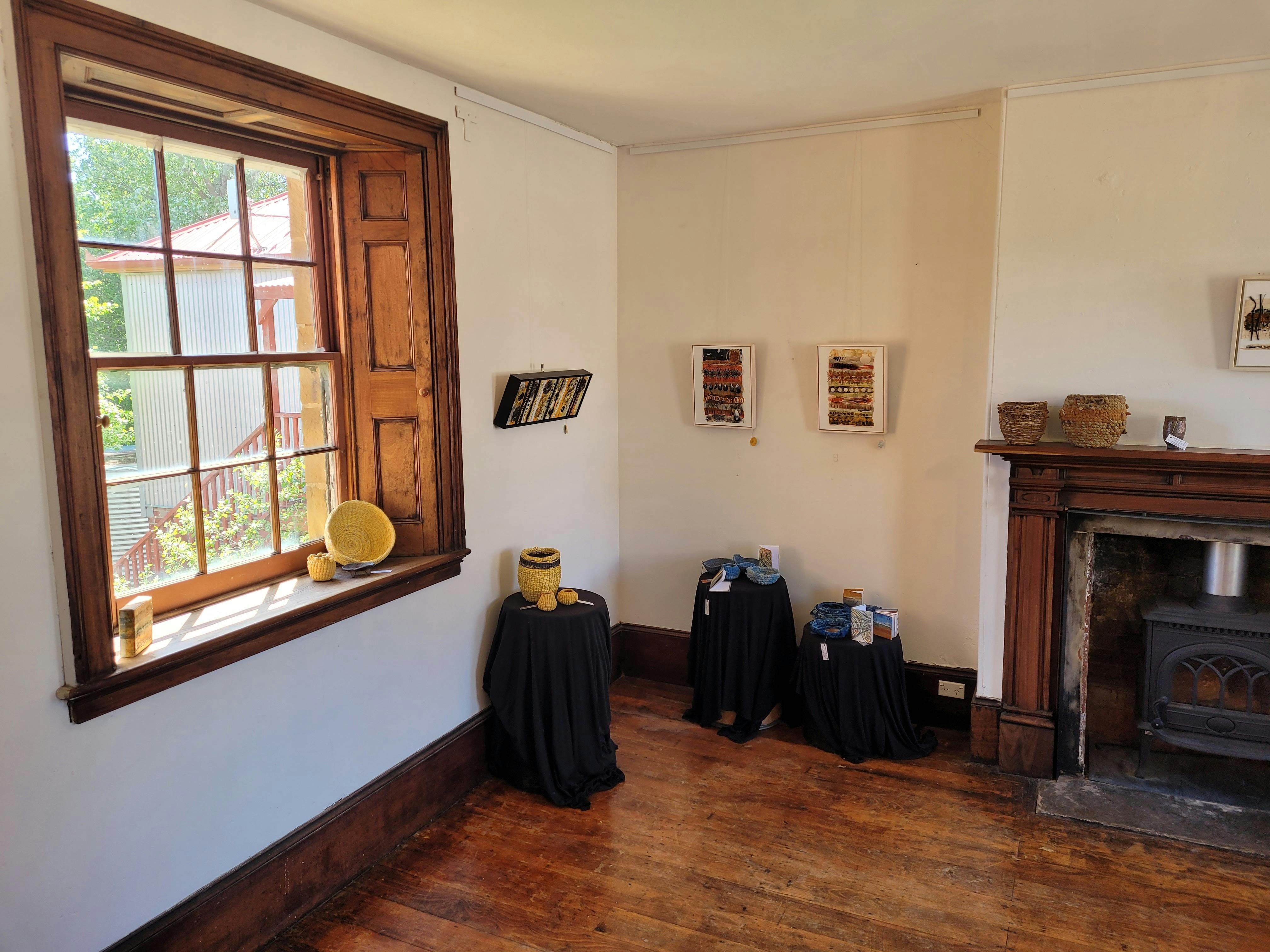 Artwork arranged in the 1845 Parlour room with timber floor and windows.