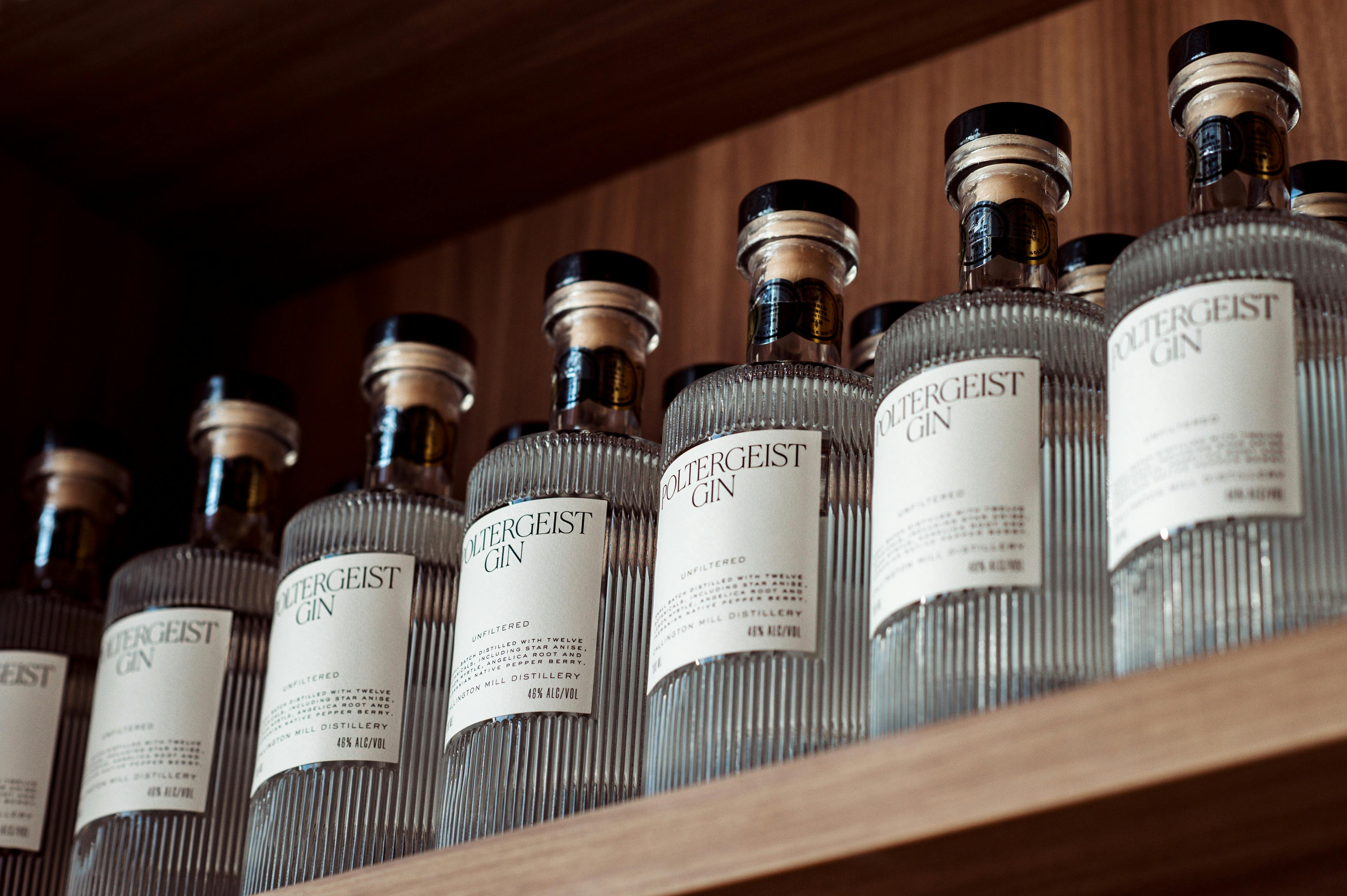 A line of six Poltergeist Gin bottles on a shelf