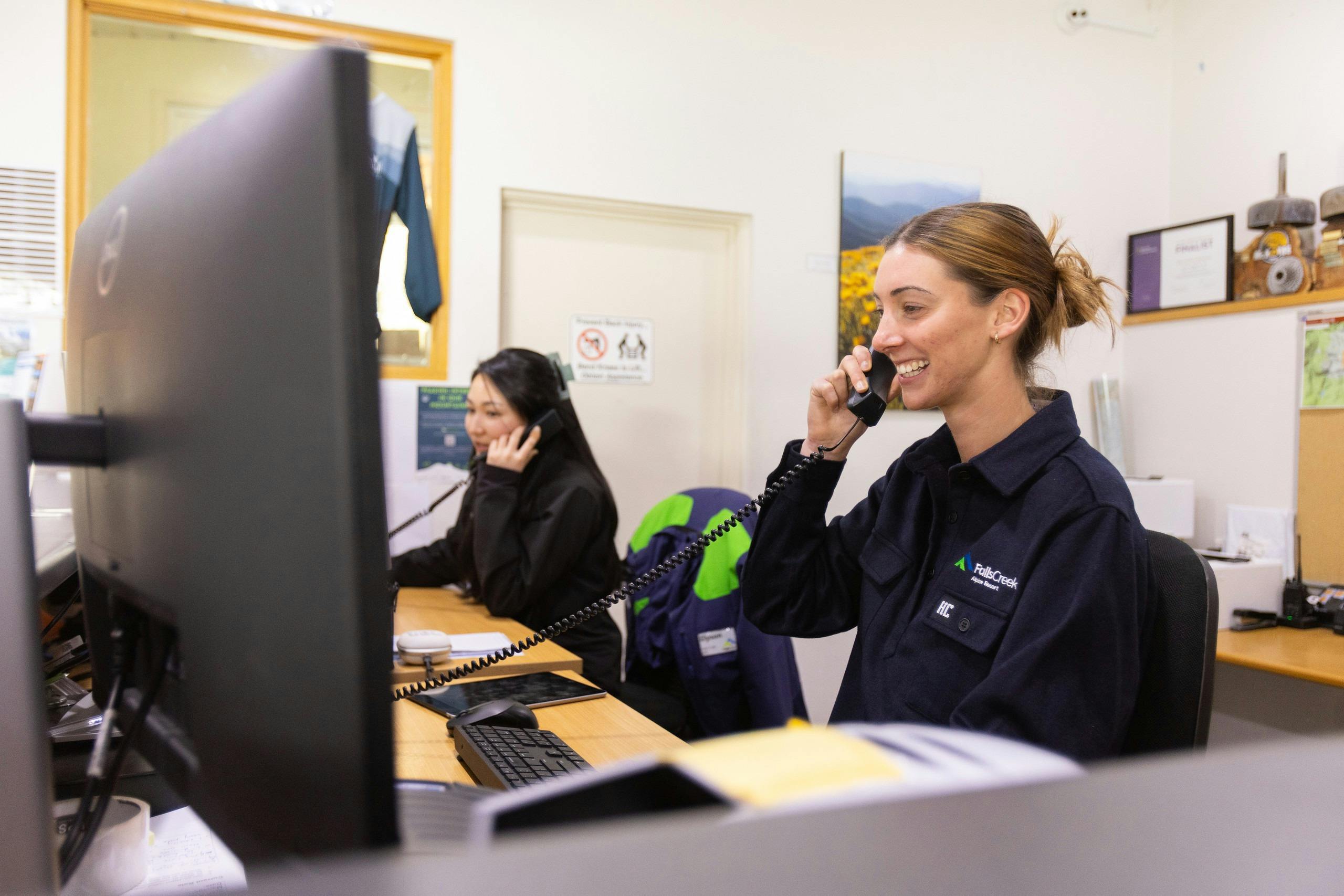 Friendly smiling staff member taking a guest enquiry phone call at the front counter.