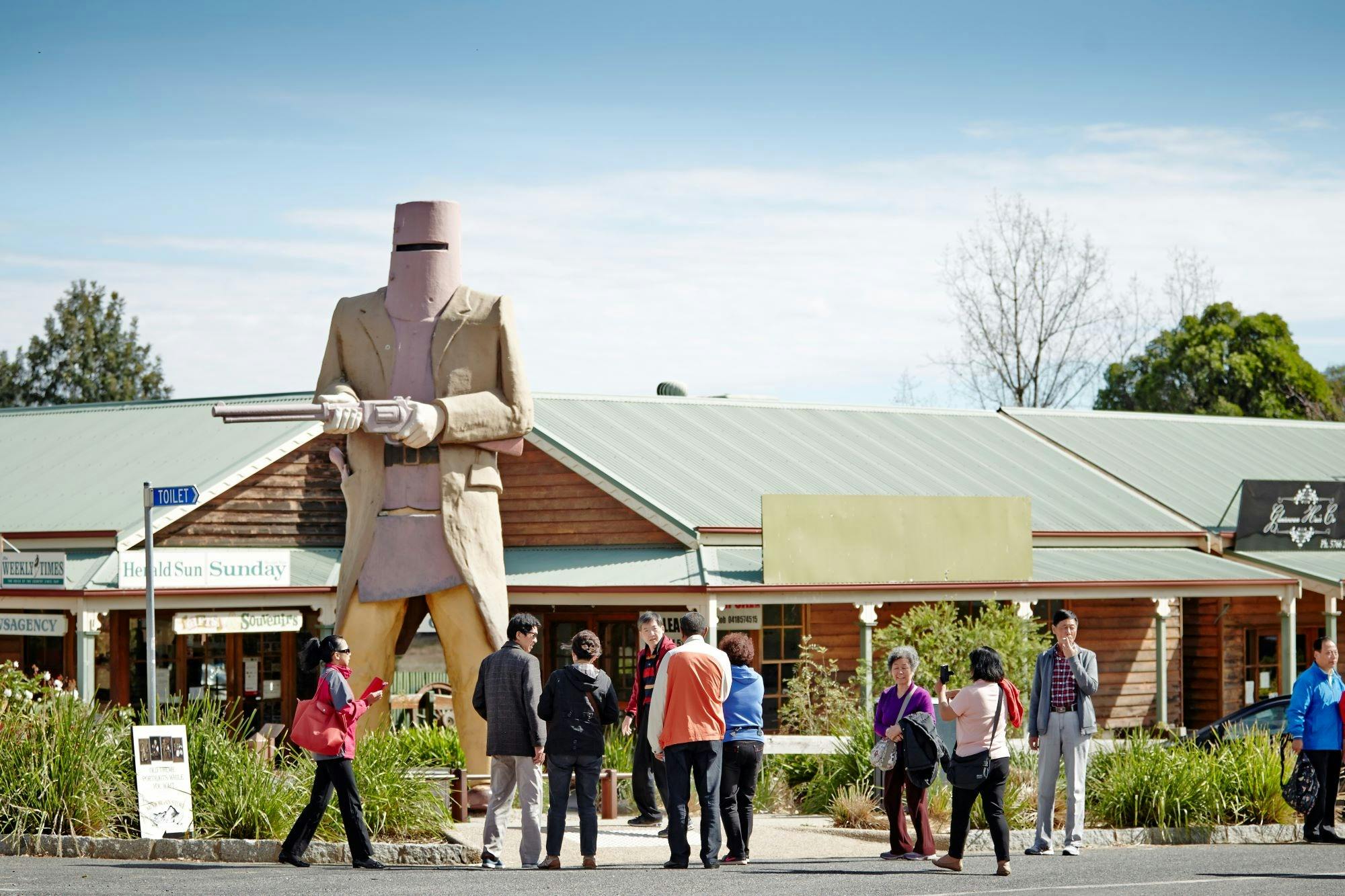 tourists taking photos of the Big Ned with shops in the background