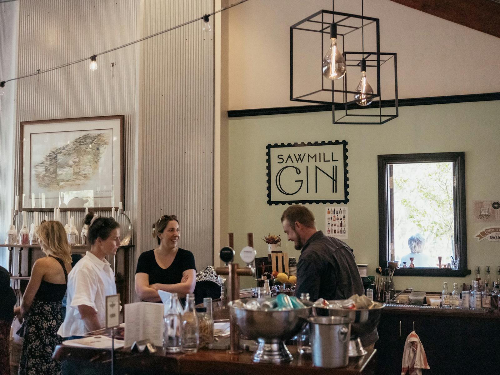 Guests ordering drinks at the bar of Sawmill Gin & The Curly Goose