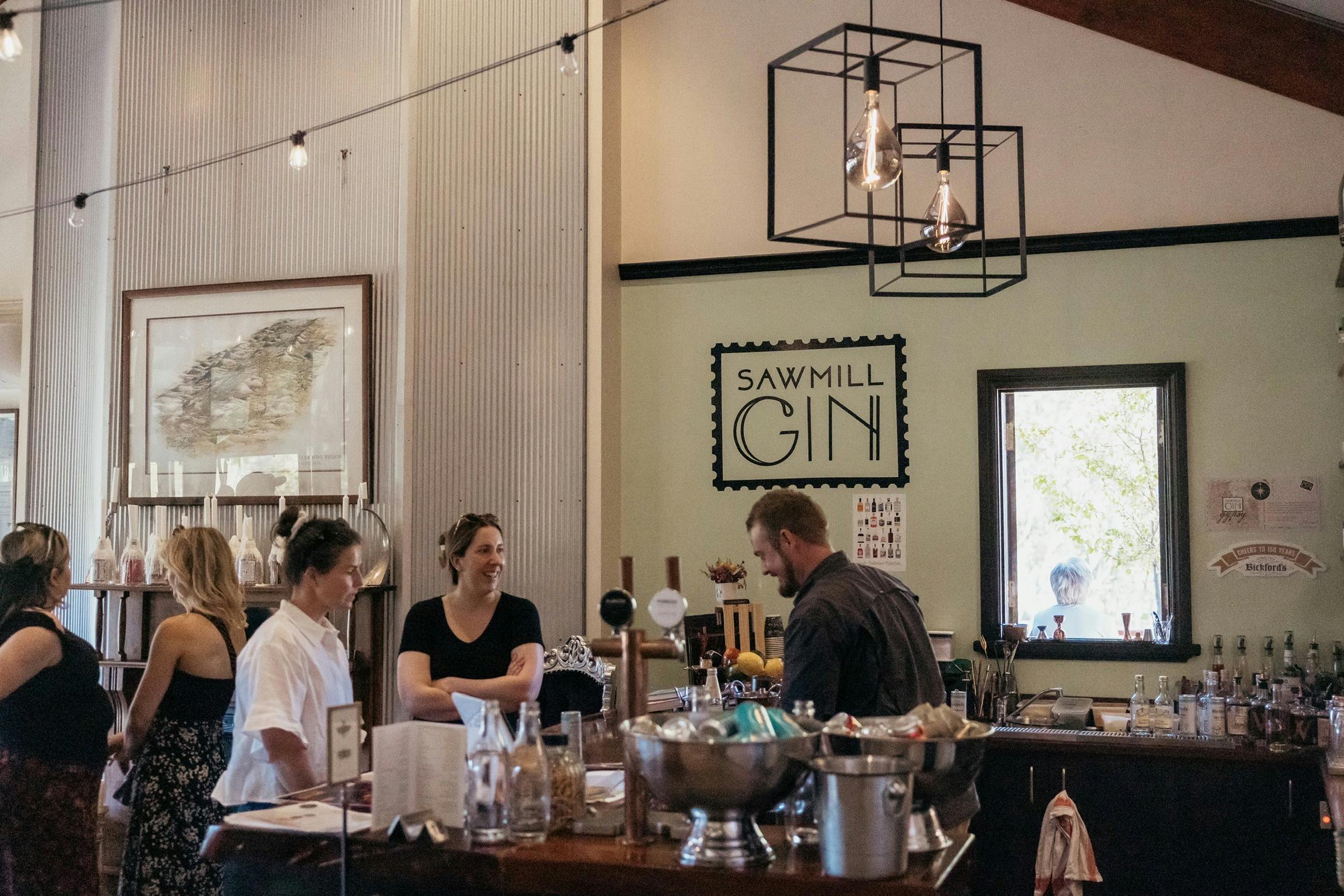 Guests ordering drinks at the bar of Sawmill Gin & The Curly Goose