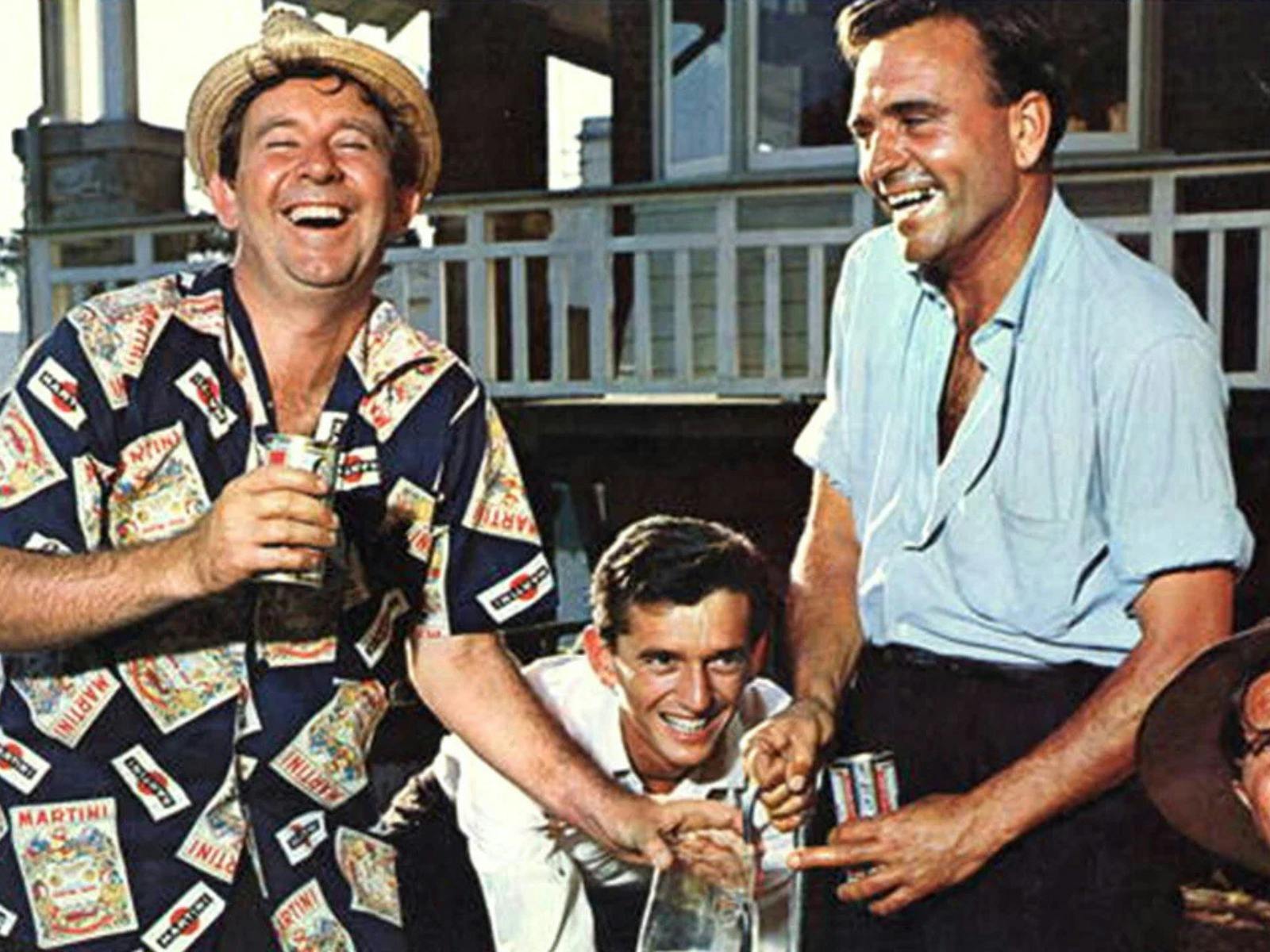 Three men laughing and drinking at the beach