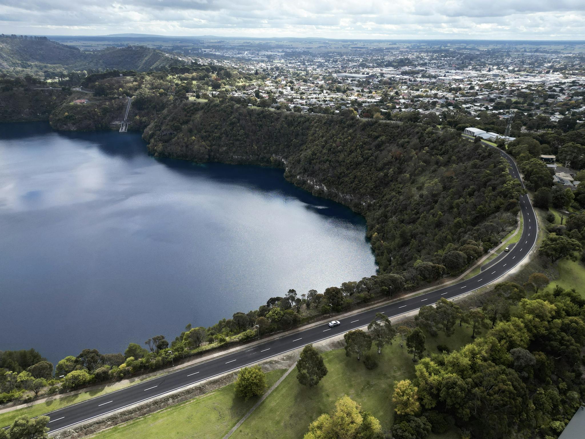 lake in a volcanic crater with city in the background
