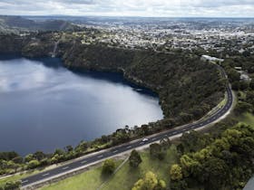lake in a volcanic crater with city in the background