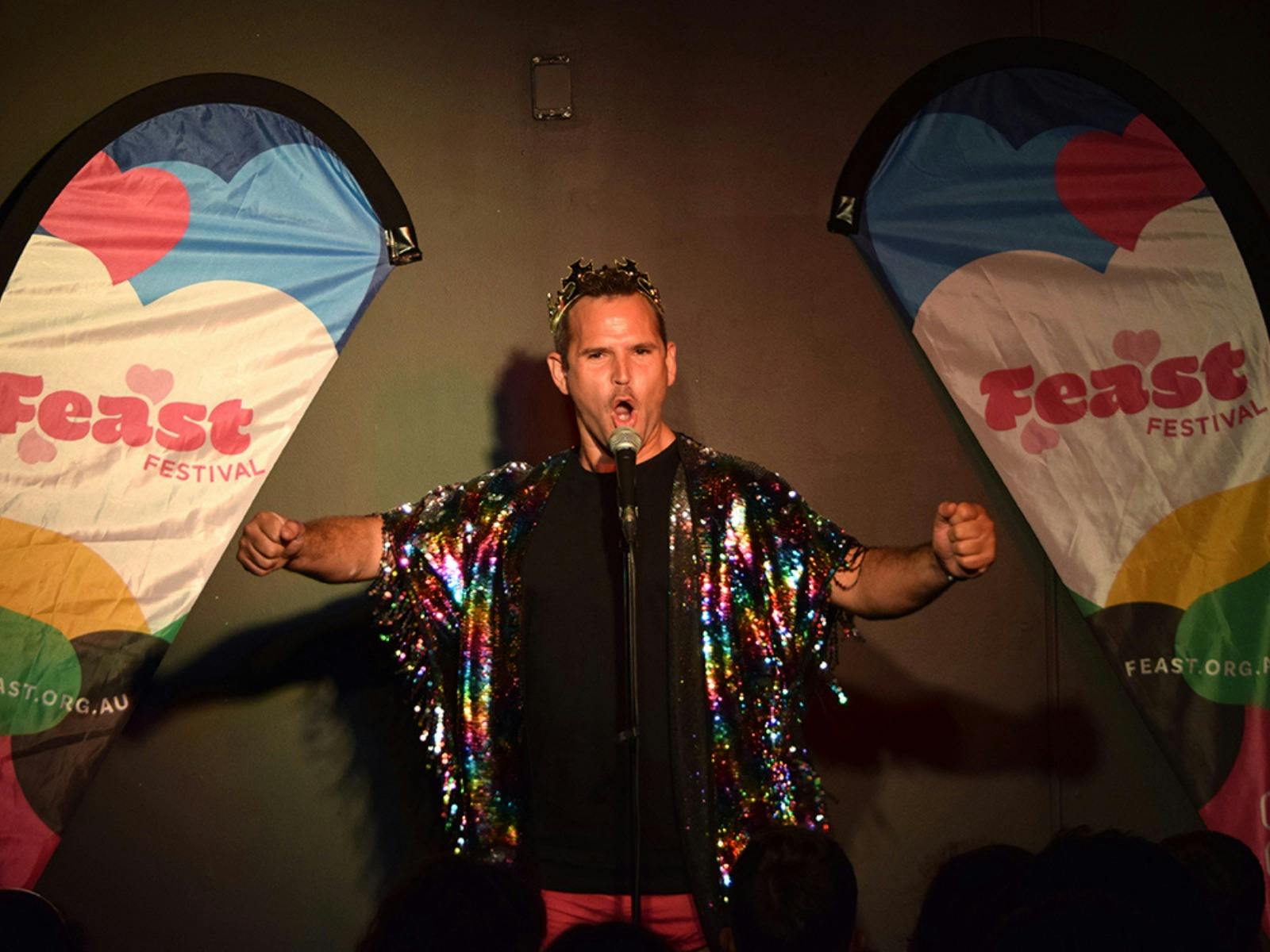 A performer wearing sequin shawl and golden crown.