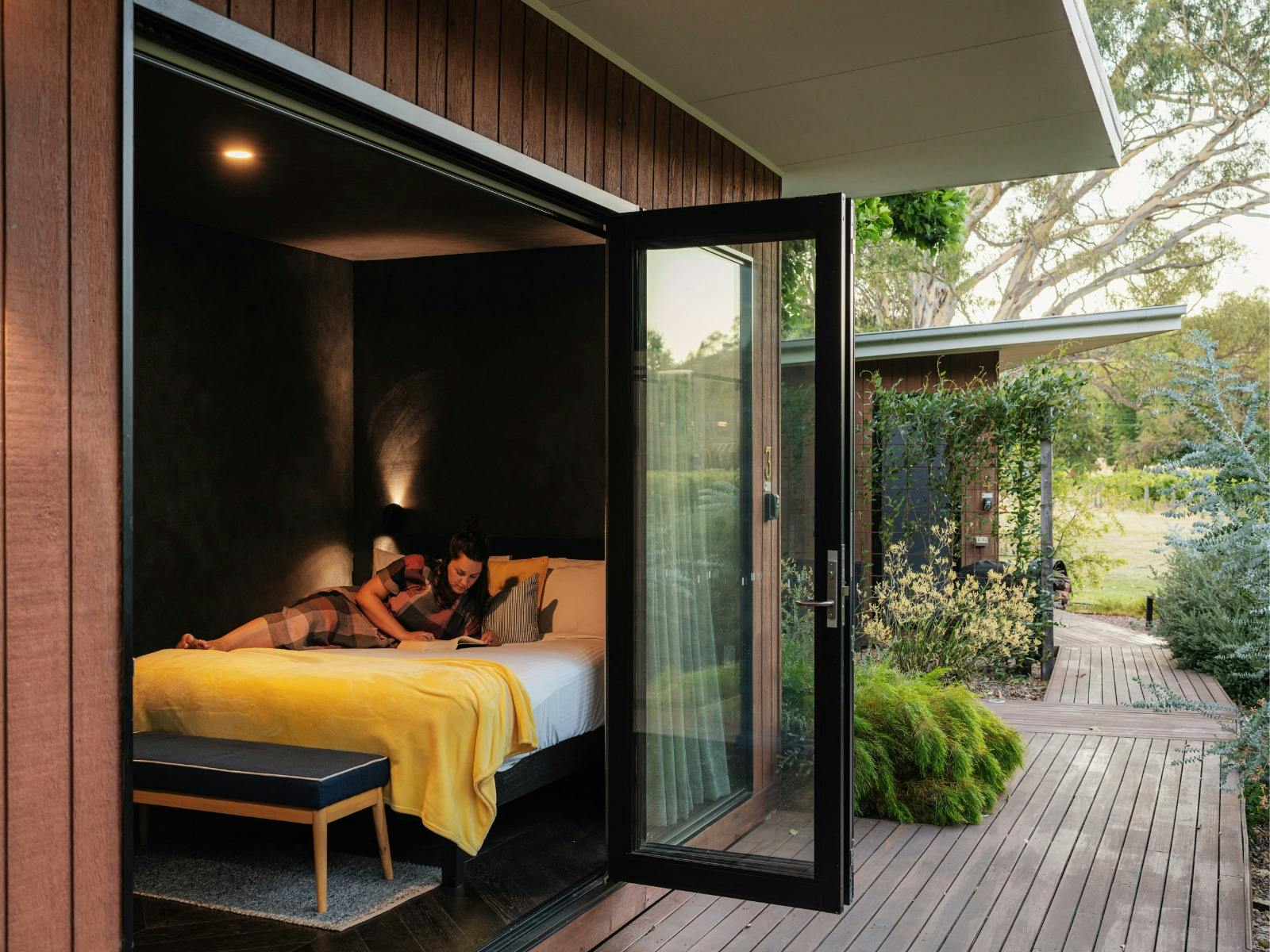 Guest enjoying reading a book on her bed at Dal Zotto Wines Petite Retreat King Valley Accommodation