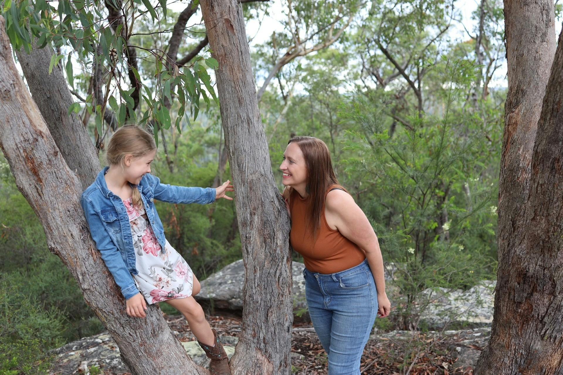 Mother and daughter leaning in tree